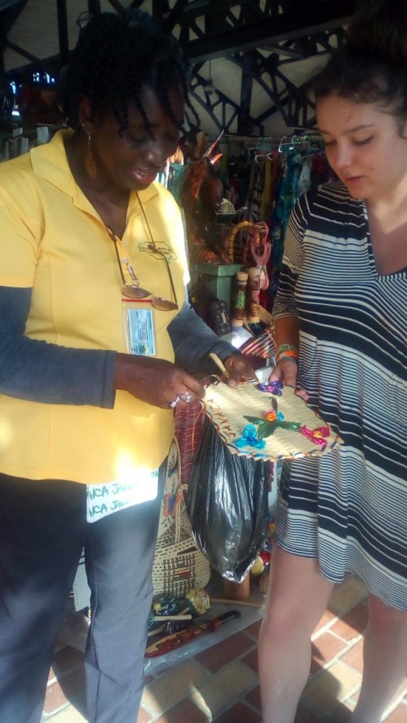 Audrey Smith (left) shows her craft item to a tourist on the Falmouth Pier.