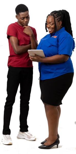 A young man in a red t-shirt and black pants consults with a female staff member in a blue shirt as she shows him something on a tablet.